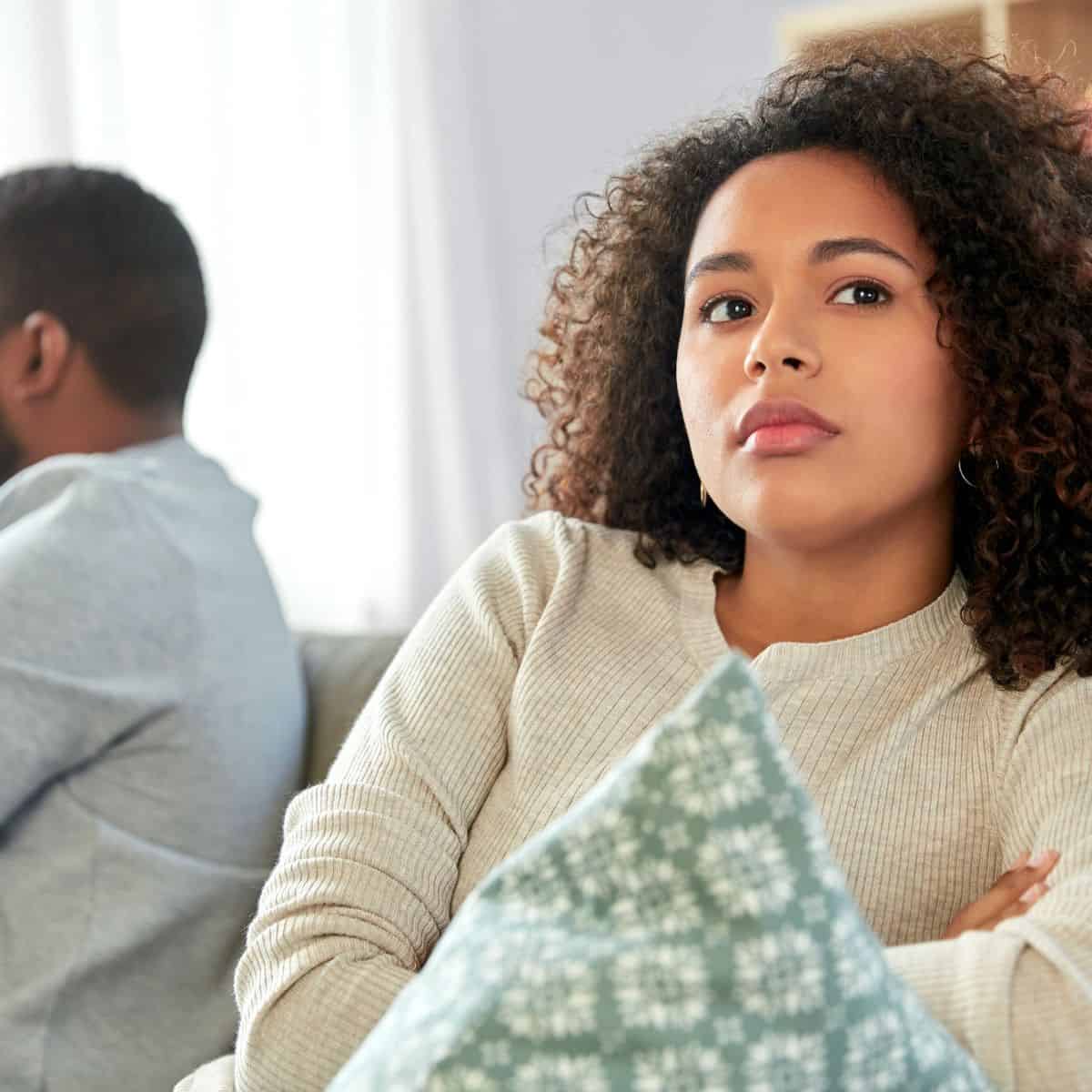 A couple in a struggling marriage, sitting in a couch far away from each other