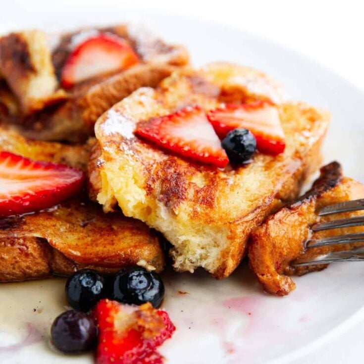 Brioche French toast with slices of stawberries and blueberries