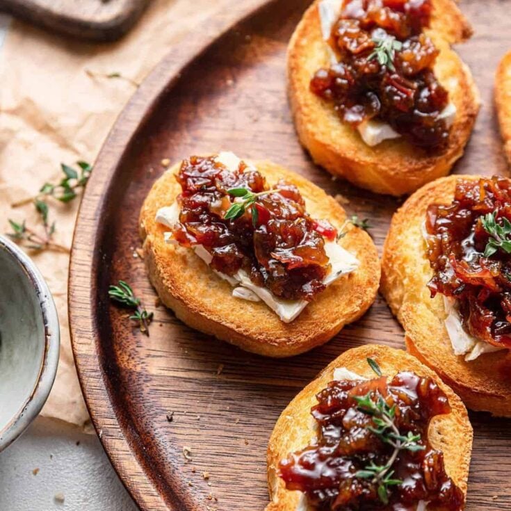 Bourbon bacon jam crostini appetizer on a wooden plate, made after reading these Fall dinner party recipes