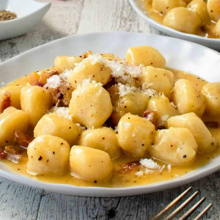 Creamy and delicious gnocchi carbonara served on a plate, made after reading these Fall dinner party recipes